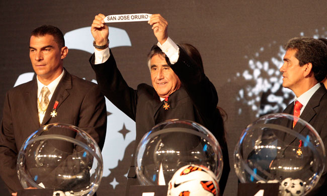 El peruano Percy Rojas muestra la etiqueta de San José en el sorteo de la Copa Libertadores junto al colombiano Farid Mondragón (i) y el boliviano Milton Melgar (d). Foto: EFE