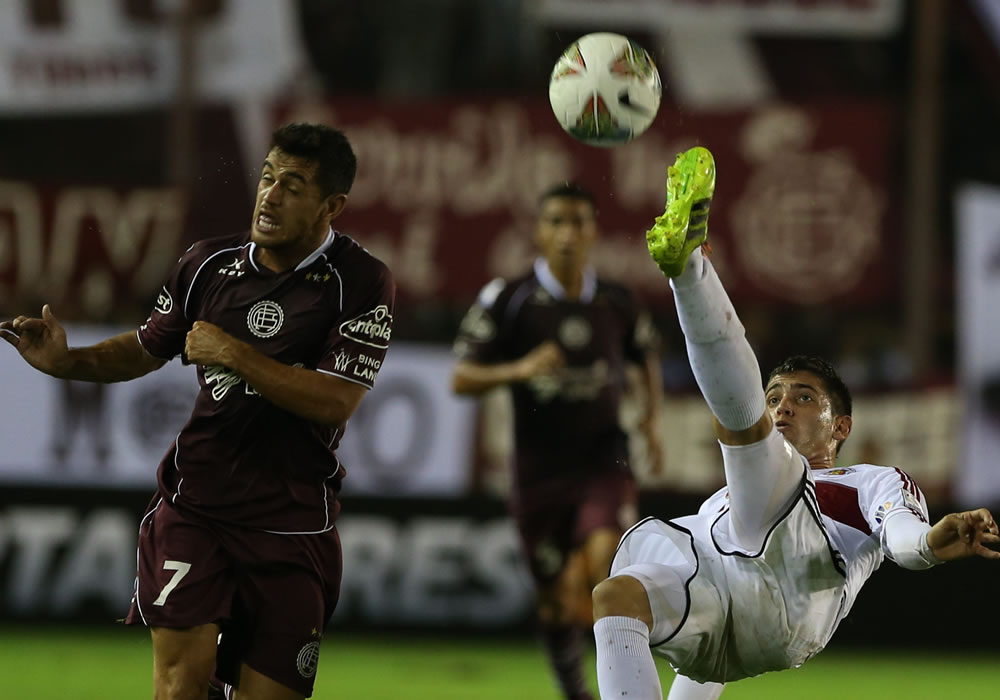 El jugador de Caracas Robert Quijada (d) patea el balón ante la marca de Lautaro Acosta (i), de Lanús. Foto: EFE