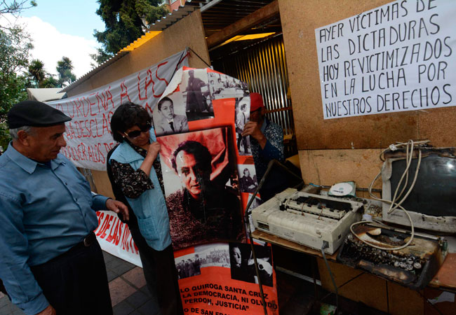 El presidente de la Plataforma de Luchadores Sociales contra la Impunidad, Julio Llanos (i) y Victoria López (d), víctima de las dictaduras, enseñan carteles reclamando por el olvido. Foto: EFE
