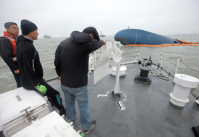 El familiar de un pasajero desaparecido rompe a llorar frete a parte del casco del ferry hundido al conocer que se suspenden las labores de búsqueda. Foto: EFE