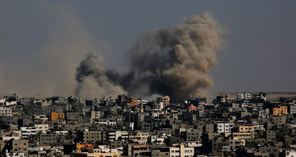 Una columna de humo se desprende de un edificio tras un ataque aéreo de Israel en el barrio de Al Shejaeiya en Gaza. Foto: EFE