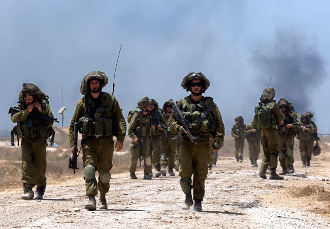 Soldados de la Infantería israelí caminan por una vía no asfaltada tras combatir en el interior de la franja de Gaza. Foto: EFE