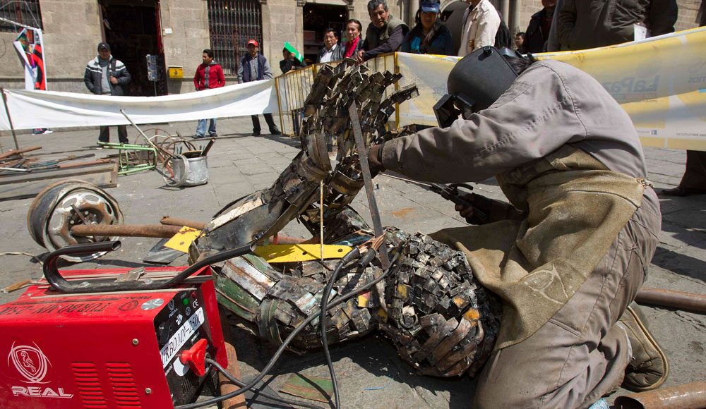 Una artista trabaja en la elaboración de una escultura a partir de chatarra, en La Paz. Foto: EFE