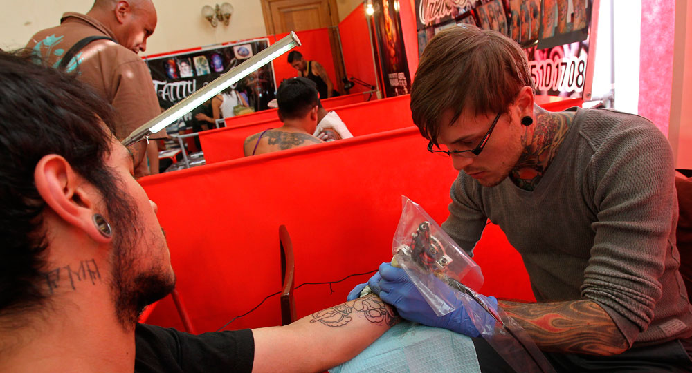 El estadounidense Nick Baxter tatúa a un asistente del encuentro de tatuadores que se realiza en la ciudad de La Paz. Foto: EFE