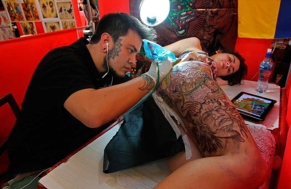 El colombiano César Hernandez en el proceso de un tatuaje, durante la primera jornada del 'Art Tattoo Bolivia 2014' que se realiza en el Club de La Paz. Foto: EFE