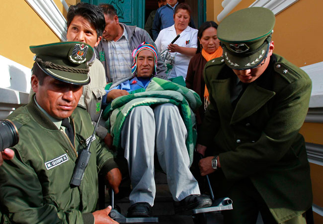 Policías ayudan al magistrado Gualberto Cusi (c), enfermo con tuberculosis, a salir de la Asamblea Legislativa Plurinacional. Foto: EFE