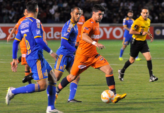 El jugador de Universitario Rubén de la Cuesta (c) disputa el balón con Jorge Torres Nilo (i) y Guido Pizarro (c) de Tigres. Foto: EFE