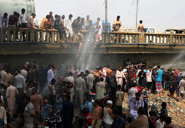 Personas intentan refrescarse junto a una tubería rota en Karachi (Paquistán), agobiados por el fuerte calor que azota esa región. Foto: EFE