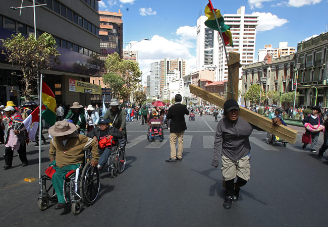 Manifestantes con discapacidad marchan por la céntrica avenida Mariscal Santa Cruz de La Paz, exigiendo un bono al gobierno. Foto: EFE