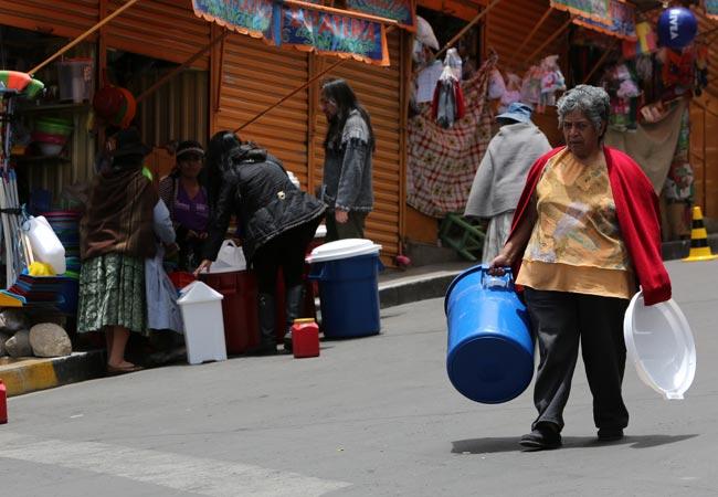 Una ciudadana camina con su recipiente para recibir agua, en la zona de Villa Copacabana, uno de los 94 barrios paceños que sufre por cortes en el suministro. Foto: EFE