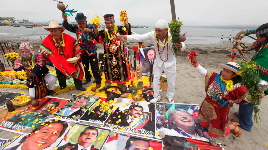 Chamanes peruanos durante un ritual sobre imágenes de mandatarios de distintos países para atraer la suerte, junto al mar de la ciudad de Lima, Perú. Foto: EFE