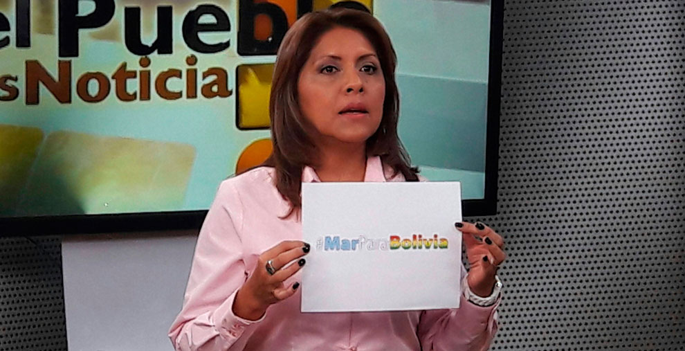 La ministra de Comunicación, Gisela López, sostiene un cartel con la leyenda #MarParaBolivia en una entrevista en el canal 7. Foto: ABI