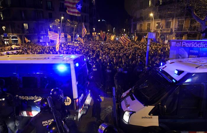 Manifestantes ondeando banderas catalanas independentistas frente a la policía antidisturbios. Foto: AFP