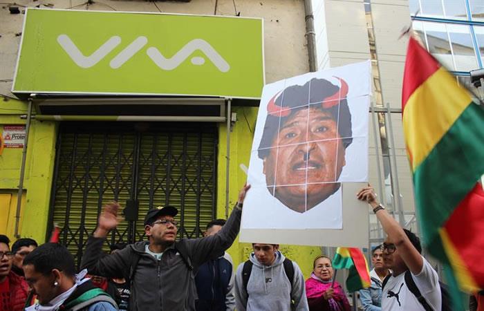 Manifestantes sostienen un cartel que caricaturiza como un demonio al presidente boliviano. Foto: EFE