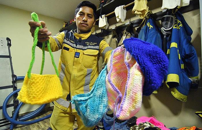 Bombero con las bolsas o "niditos" que fueron tejidos por los voluntarios. Foto: EFE
