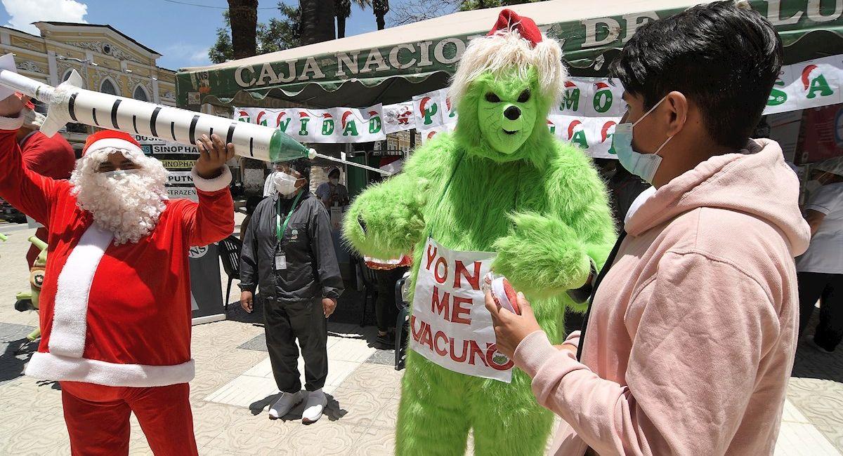 Ciudadanos disfrazados de Papá Noel y el Grinch animan a vacunarse contra la COVID-19. Foto: EFE